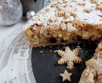 Eine aufgeschnittene weihnachtliche Bratapfel-Tarte auf einem Teller mit Plätzchen im Vordergrund.