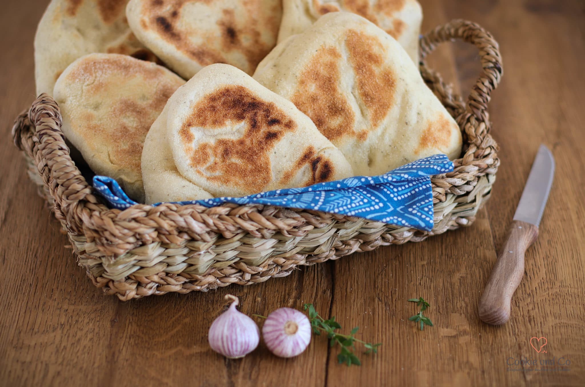 Grill-und Pfannenbrot in einem Brotkorb mit einem Messer und Knoblauchzehen daneben.