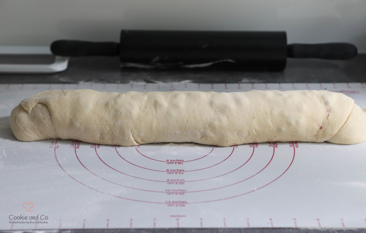 Hefeteig für Hefeschnecken mit Blaubeerfüllung aufgerollt.