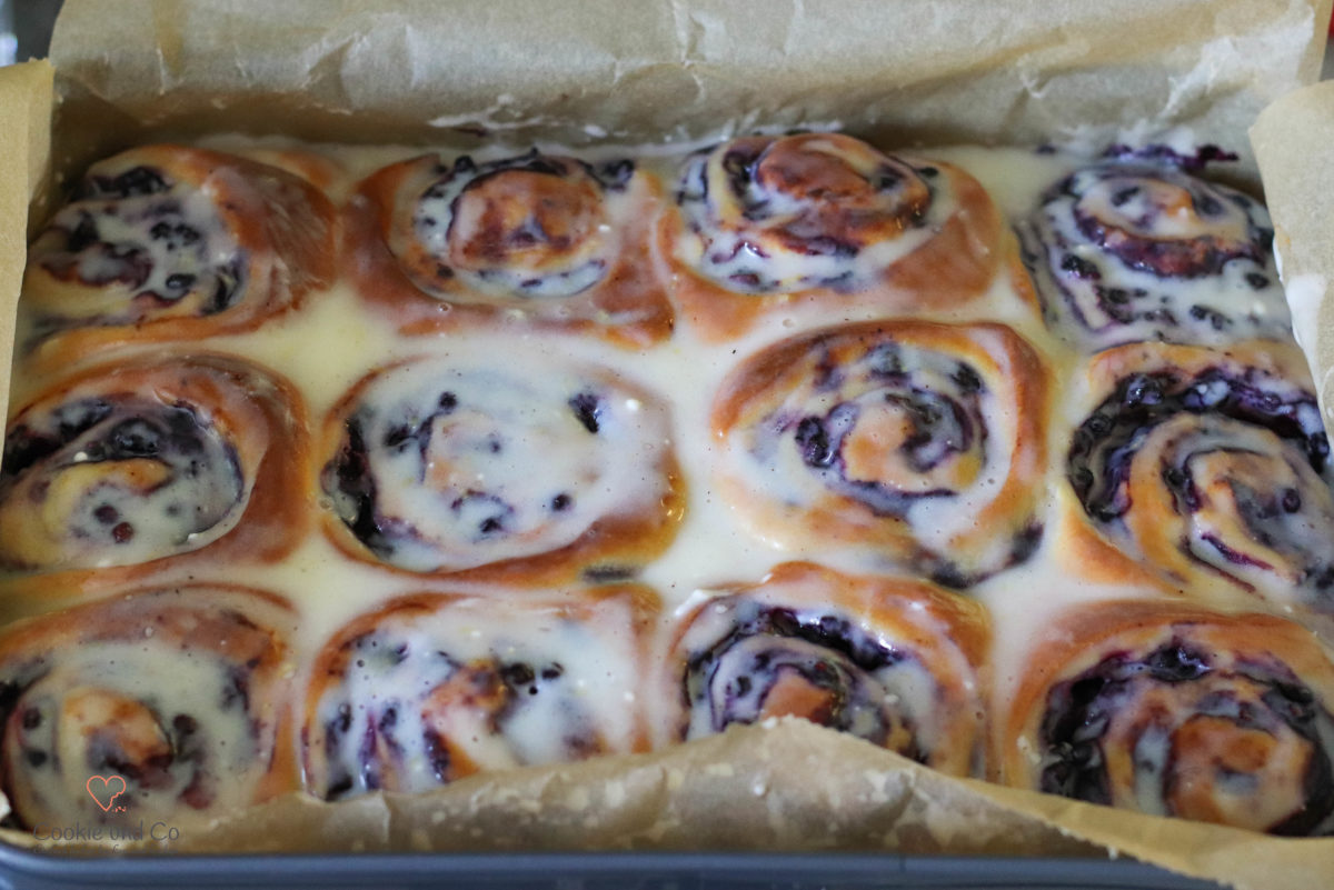 Saftige Hefeschnecken mit Blaubeeren frisch gebacken in der Backform mit Zuckerguss.