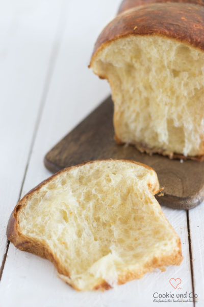 Französische Brioche angeschnitten auf einem Holzbrett.
