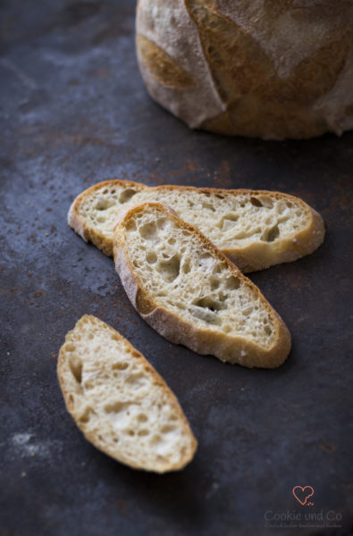 Mediterranes No Knead Bread in Scheiben auf einem alten Backblech.