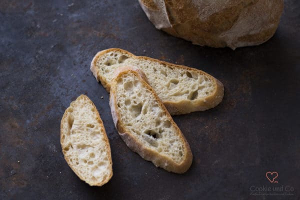 Mediterranes No Knead Bread in Scheiben auf einem alten Backblech.