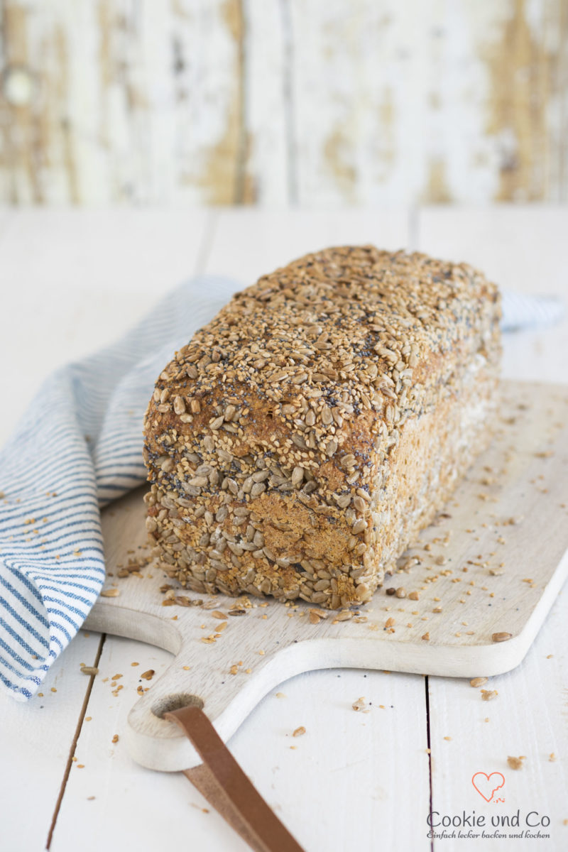 Dinkel-Möhren-Vollkornbrot mit Saaten auf einem Holzbrett.