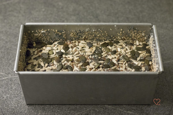 Teig für ein Dinkel-Möhren-Vollkornbrot mit Saaten in einer Kastenform.