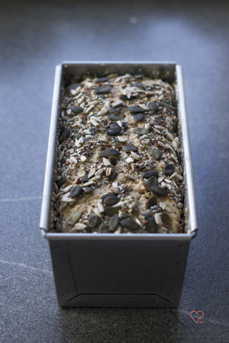 Teig für ein Dinkel-Möhren-Vollkornbrot mit Saaten in einer Kastenform.