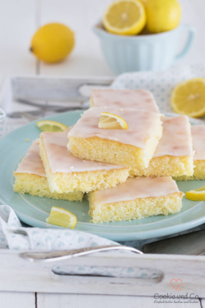 Zitronenkuchen vom Blech auf einem Teller mit Zitrone