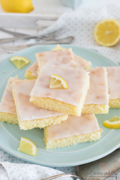 Zitronenkuchen vom Blech auf einem Teller mit Zitrone