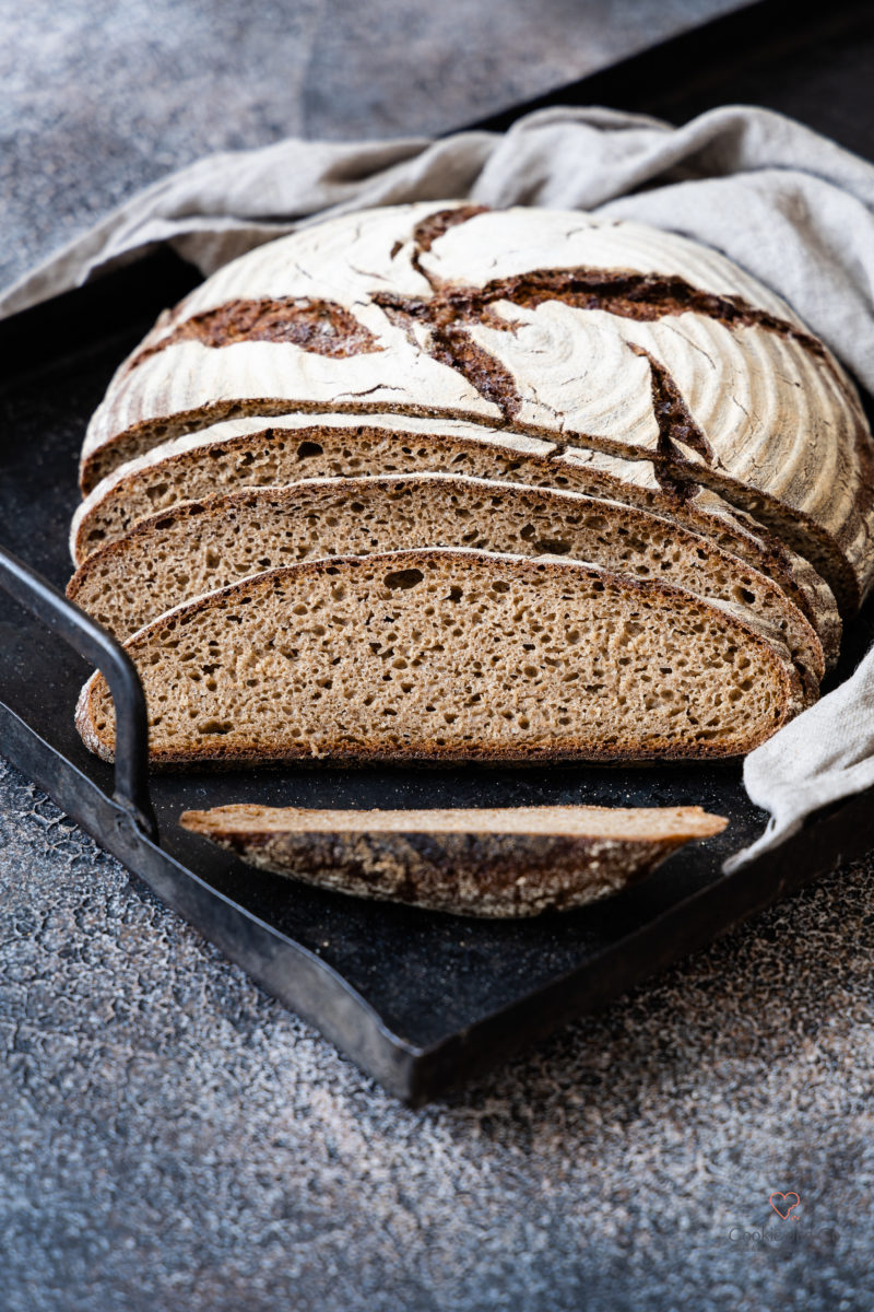 Saftiges Roggenmischbrot aufgeschnitten auf einem alten Blech. Lockere Krume.