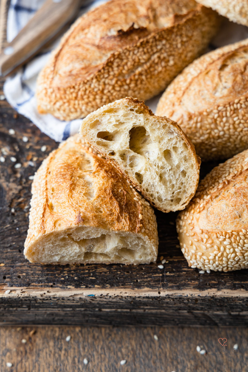 Goldies - Frühstücksbrötchen mit  Übernachtgare und Sesam auf einem Holzbrett.