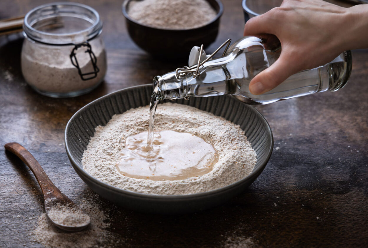 Schüttflüssigkeit, die in eine Schüssel mit Mehl gegossen wird. Der Rest wird während der Bassinage hinzugefügt am Ende des Knetvorgangs. 