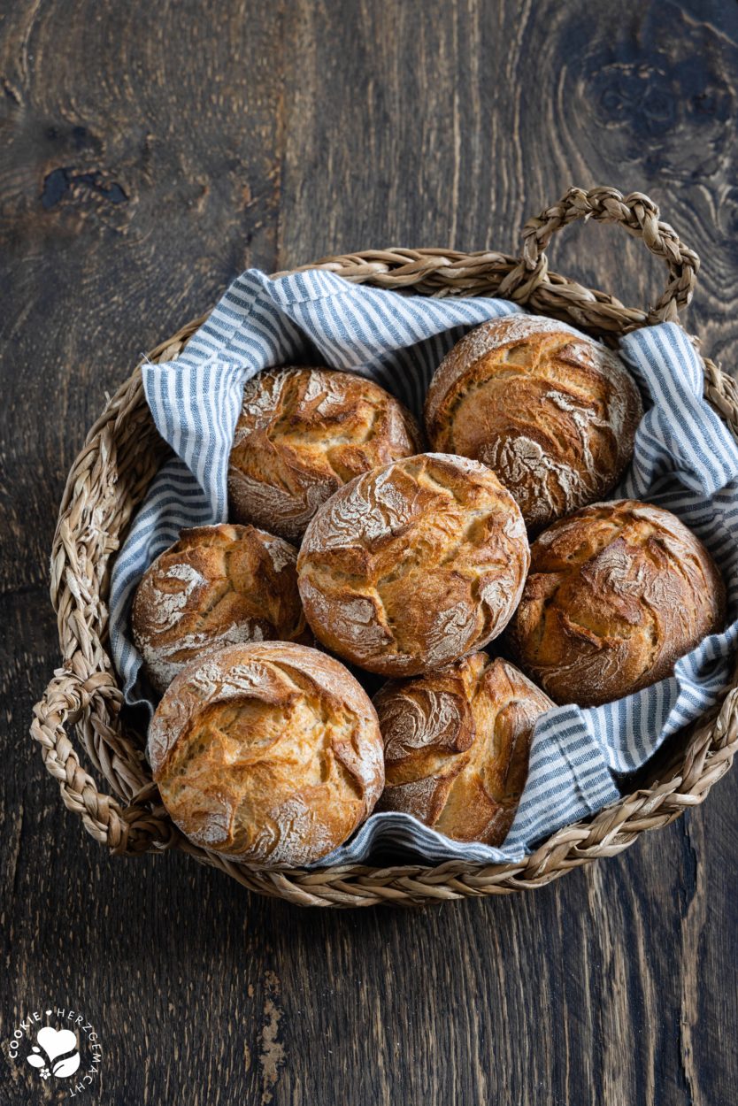 Rustikale Auffrischbrötchen mit Sauerteigresten in einem Brötchenkorb mit einem Blau gestreiften Tuch. Die Brötchen haben einer aromatische, lockere Krume und knusprige Kruste.