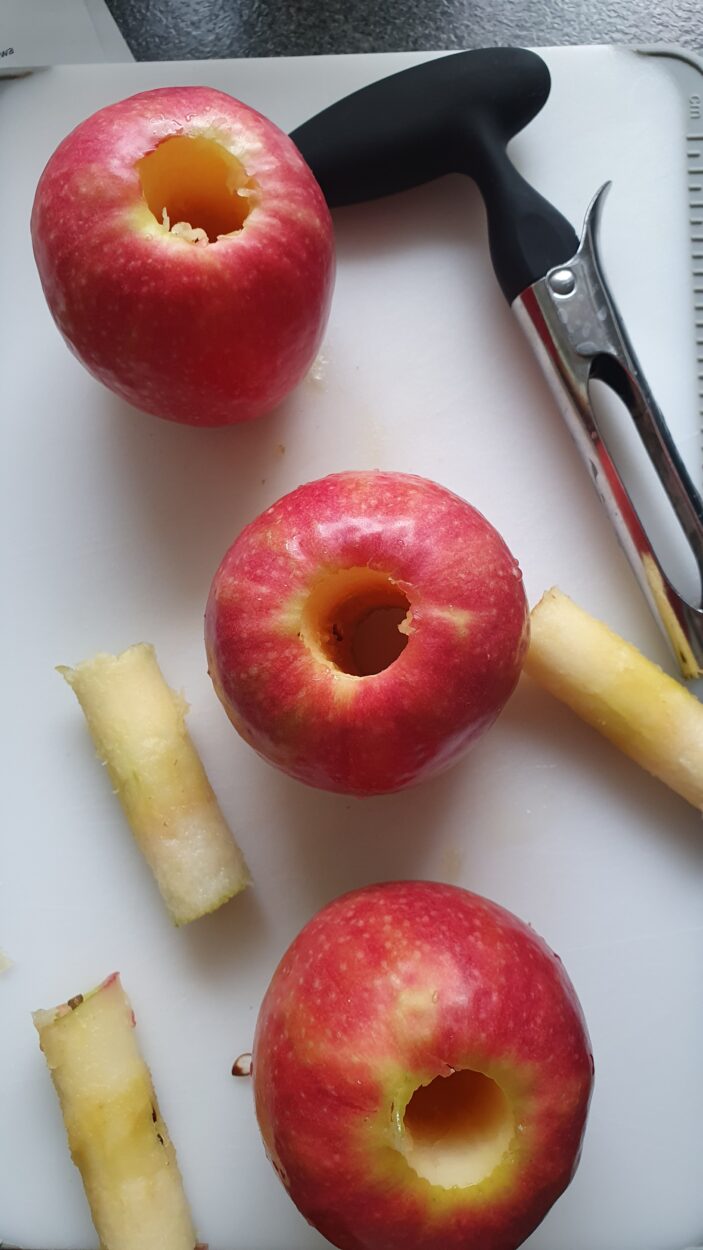 Entkernte Äpfel auf einem Schneidebrett.