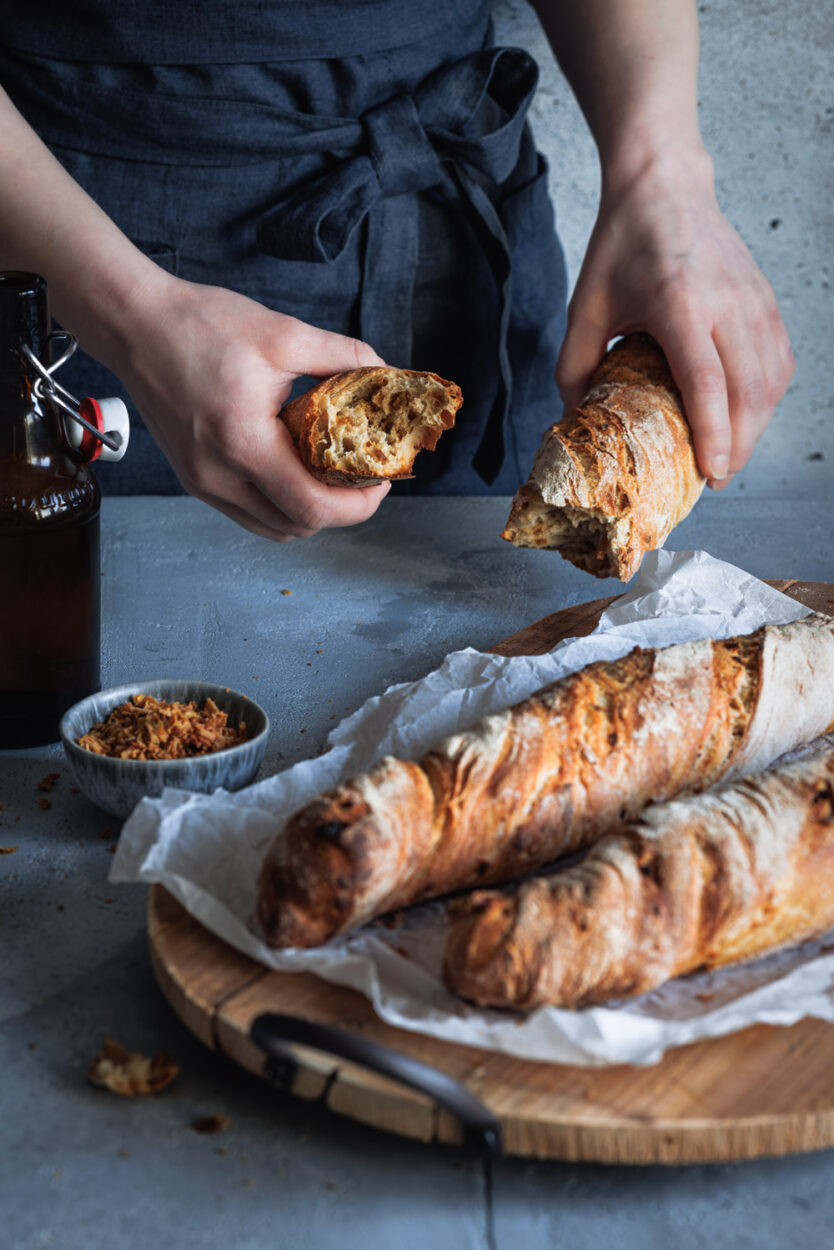 Zwiebel-Wurzelbrot mit einer Flasche Bier und einem Schälchen mit Röstzwiebeln im Hintergrund. 