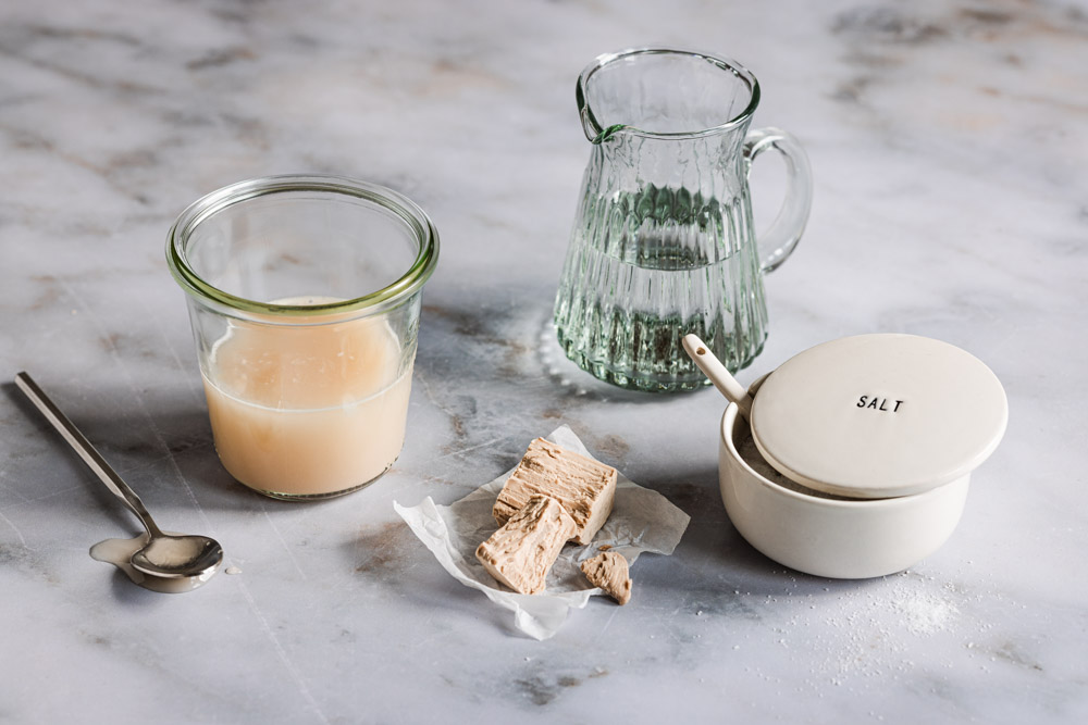 Salz-Hefe-Verfahren_ Salz-Hefe-Lösung in einem Einmachglas mit frischer Hefe, Wasser und Salz sowie einem Löffel daneben. 