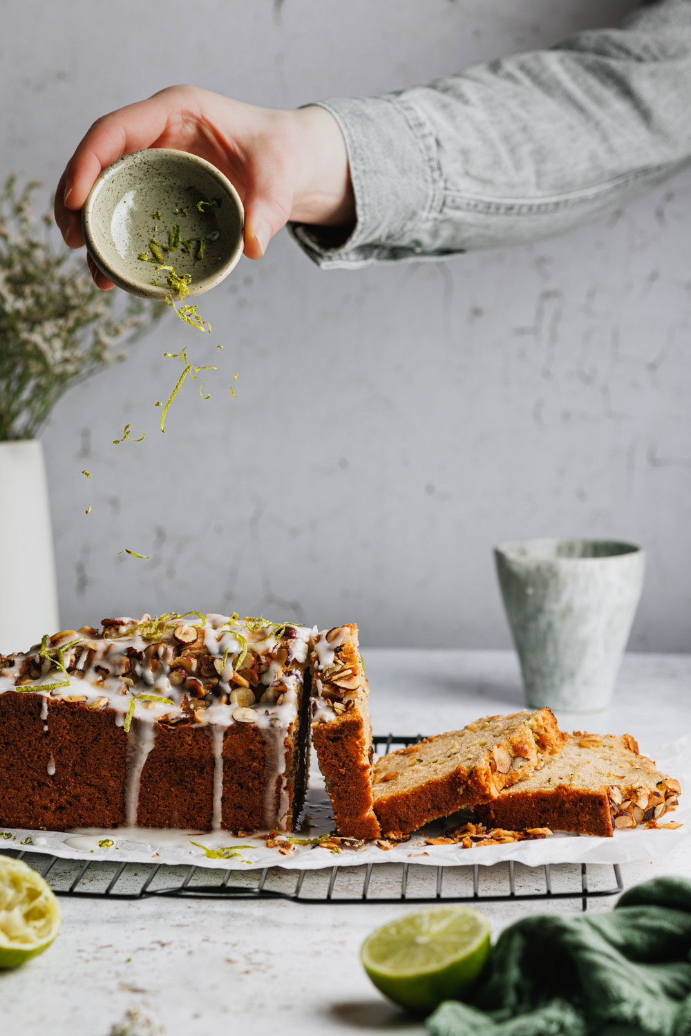 Zucchini-Nuss-Kuchen mit Nüssen auf einem Kuchengitter auf den Limetten-Zesten gestreut werden. 