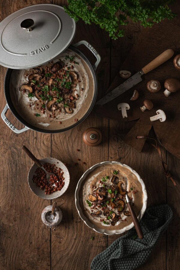Pilzrahmsuppe mit gebratenen Champignons, Speck und Petersilie.