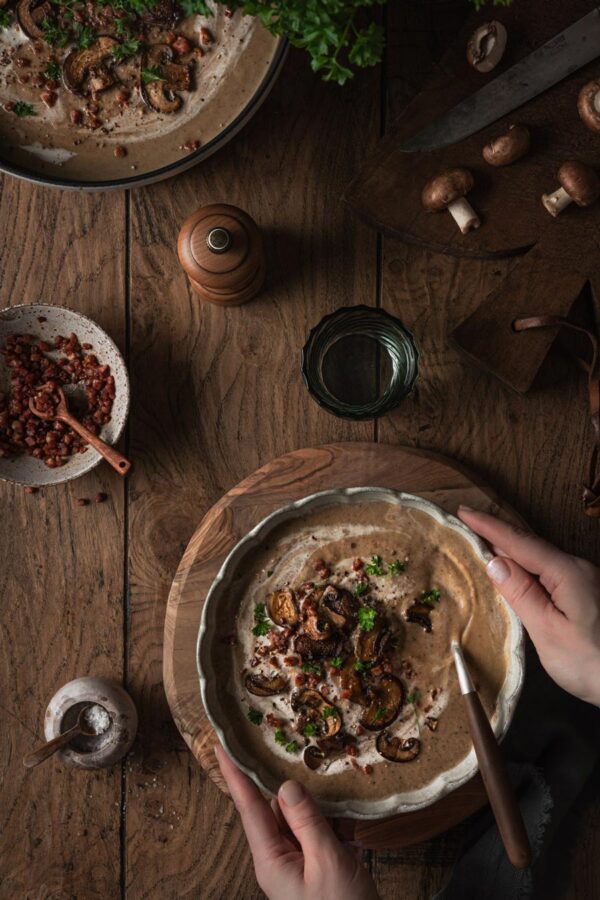 Herbstsuppe mit braunen Champignons, Steinpilzen und Pfifferlingen, getoppt mit gebratenen Champignons, Speck und Petersilie.