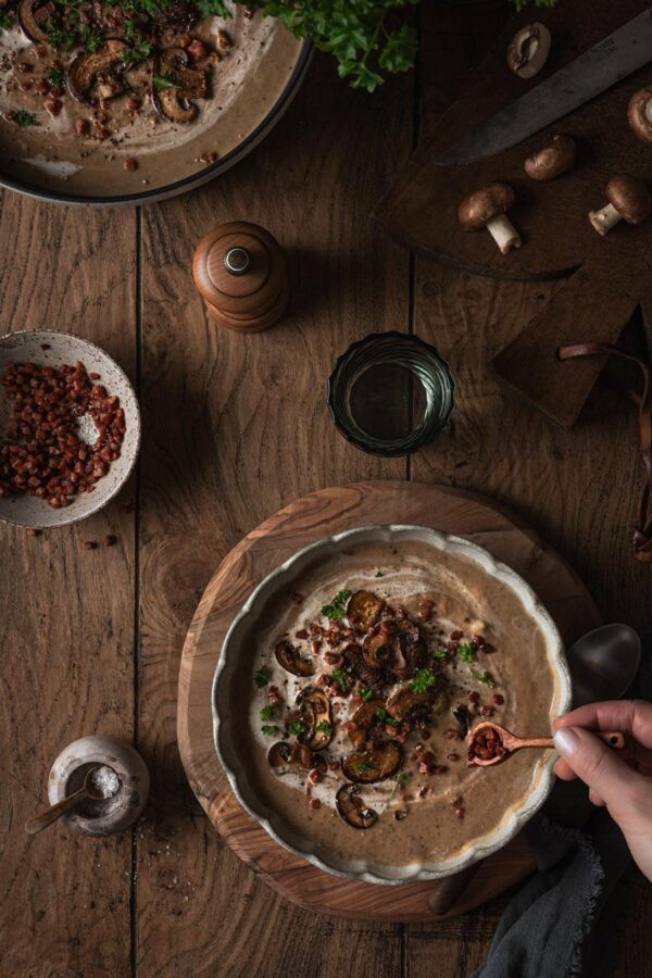Herbstliche Pilzsuppe mit gebratenen Champignons, Speck und Petersilie.