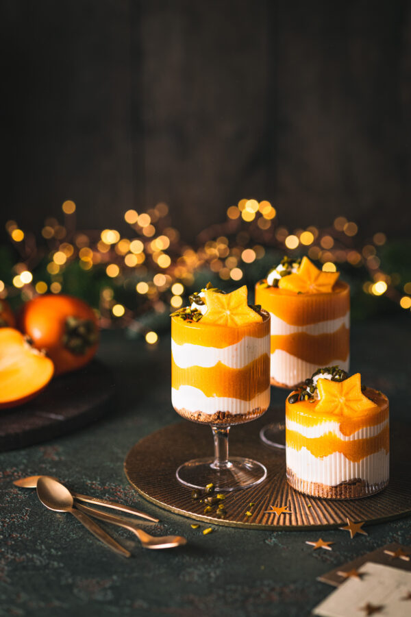 Weihnachtliches Kaki-Schichtdessert mit Joghurt-Creme und Kaki-Soße getoppt mit Pistazien. 