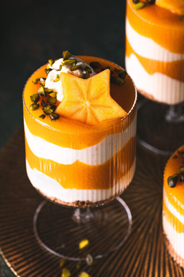 Weihnachtliches Kaki-Schichtdessert mit Joghurt-Creme und Kaki-Soße getoppt mit Pistazien. 