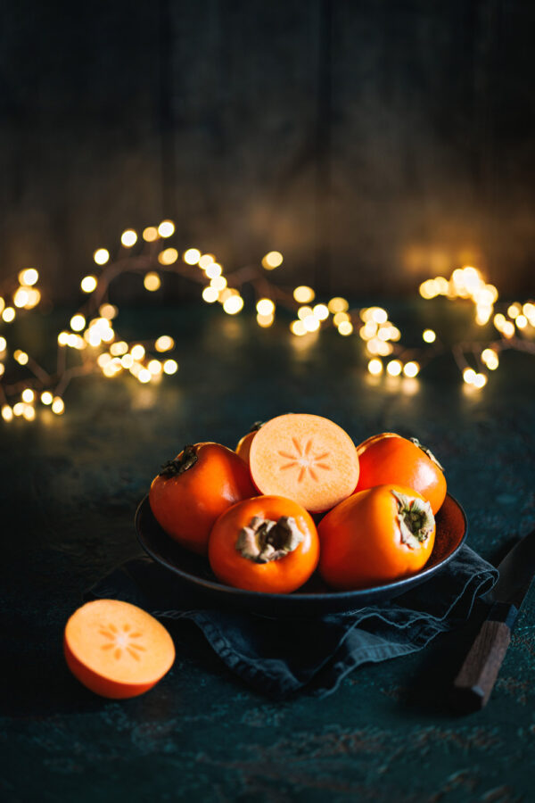Kakis n eine Schale mit einer Lichterkette im Hintergrund. 
