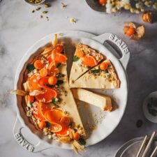 Orangentarte mit Mürbeteigboden und cremiger Füllung und einer Deko mit Orangen, Pistazien, weißer Schokolade und Physalis.